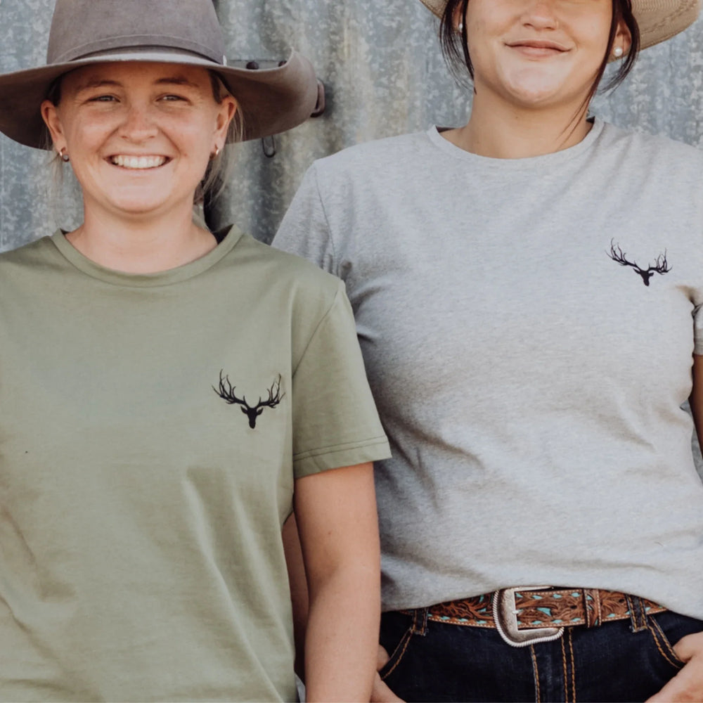 Two men and two women stand in front of a shed wearing Rawhide Rural staple tees