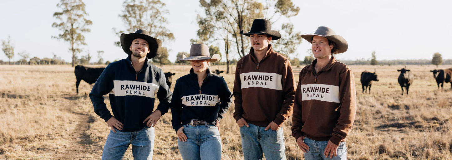 Three men and one woman stand in a paddock wearing Rawhide Rural Quarter Zip Jumpers