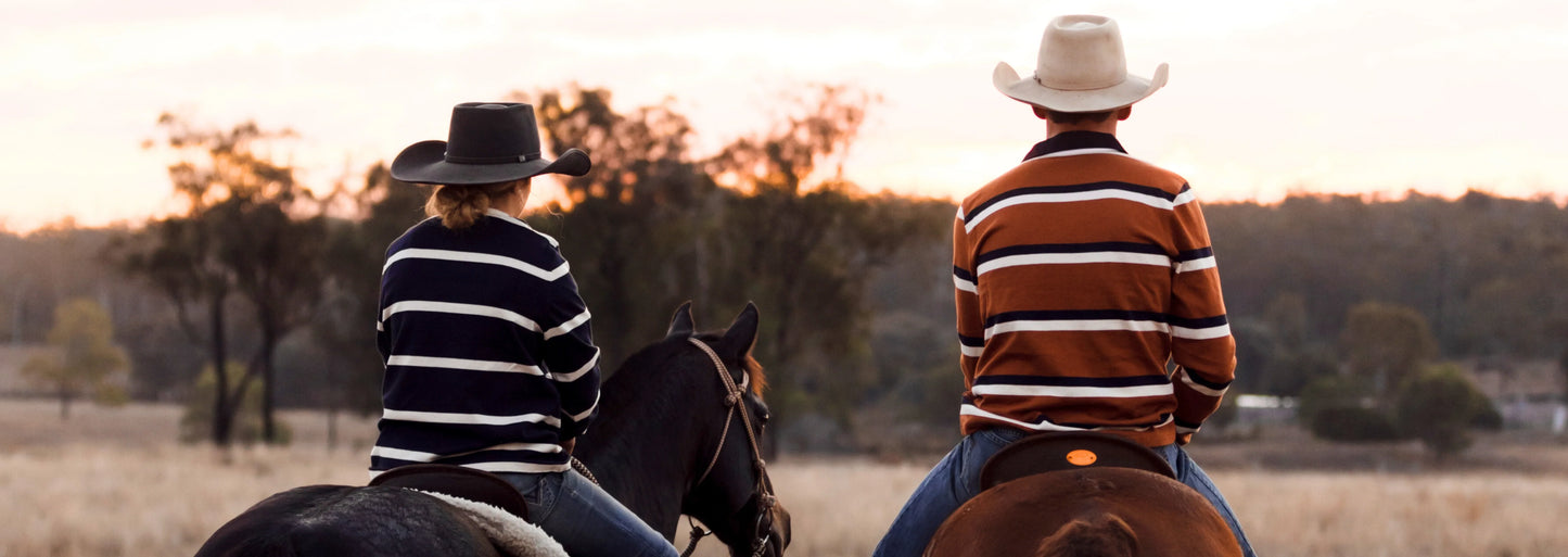 A man and a woman on horses wearing Rawhide Rural rugby jumpers