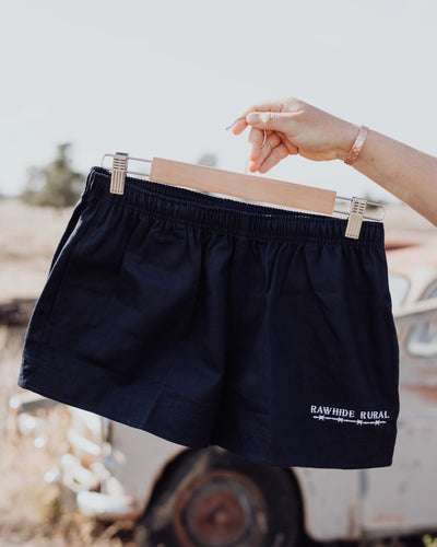Navy shorts on a hanger with a blurred outdoor background
