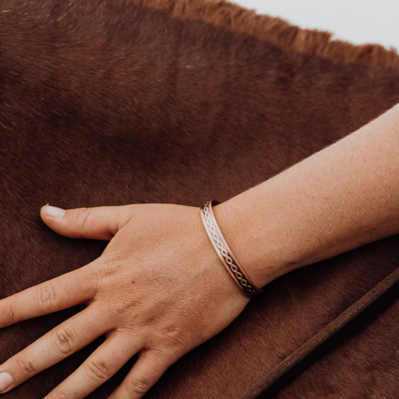 Hand wearing a twisted copper band on a horse.