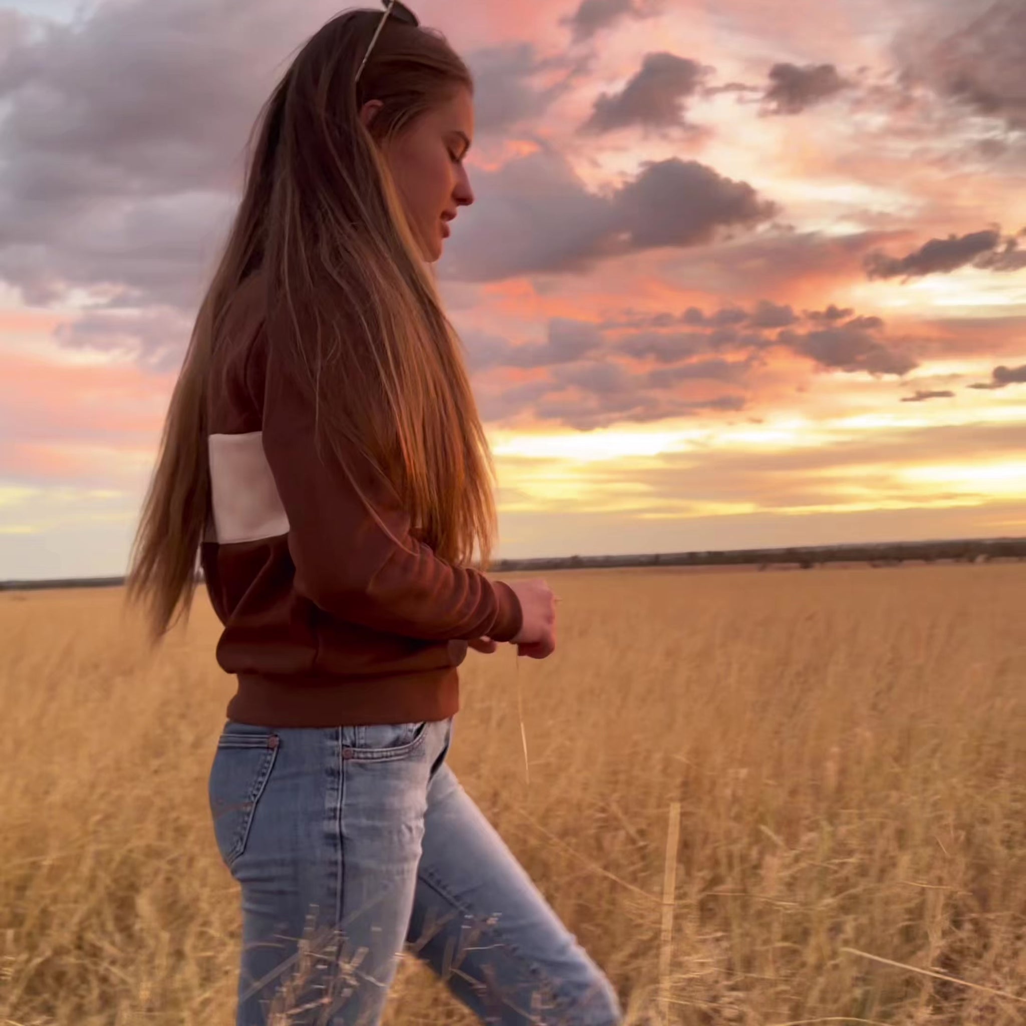 Woman walking through paddock wearing Rawhide Rural jumper.